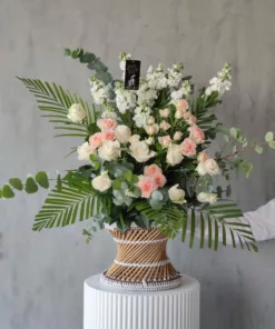 This stunning bouquet of flowers in a small wicker stool is the perfect way to brighten up any room. Soothing to the eyes, the arrangement features a variety of blooms in pastel shades. The flowers are arranged in a rustic wicker base, which adds to the overall charm of the bouquet. This arrangement  is perfect for any occasion, whether you're looking for a gift for a loved one, a centerpiece for a special event, or simply want to add a touch of beauty to your home décor. 