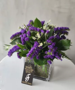 This elegant vase is filled with a beautiful arrangement of purple flowers. The arrangement is perfect for adding a touch of romance and sophistication to any home décor.
